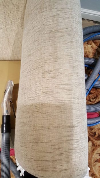 Professional upholstery cleaning in Burwell – sofa arm half-cleaned showing amazing contrast and professional hand tool in action.