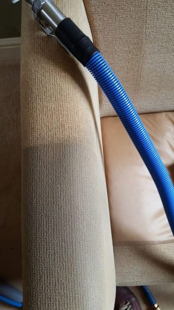 Professional upholstery cleaning in progress on a fabric sofa using deep steam extraction.