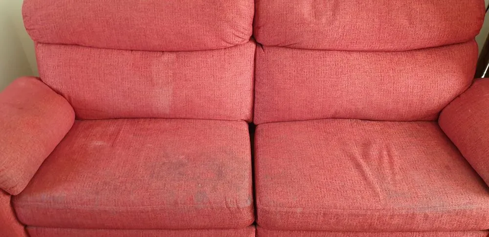 Red sofa with stains before professional upholstery cleaning in Ely