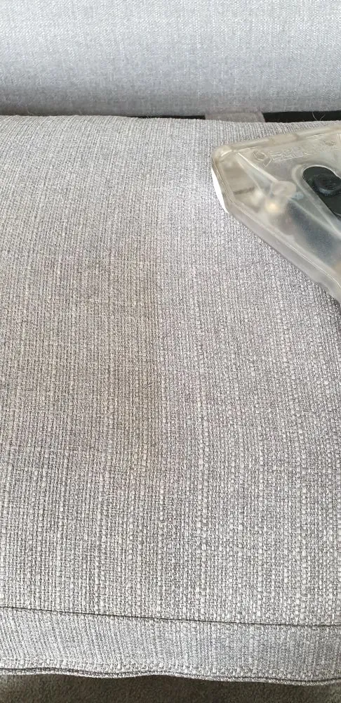 Halfway through upholstery cleaning on a grey sofa in Newmarket – showing clear difference between dirty and clean fabric.